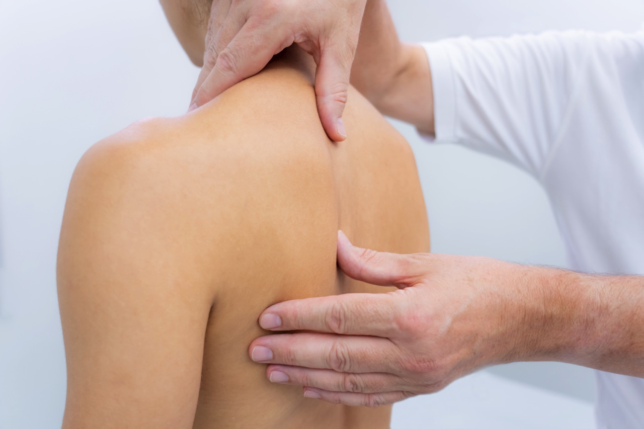 Young woman receiving shoulder massage in a physiotherapy center